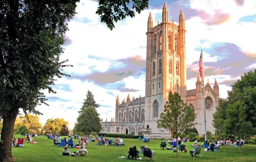 的 Trinity College Chapel with students sitting on the grass